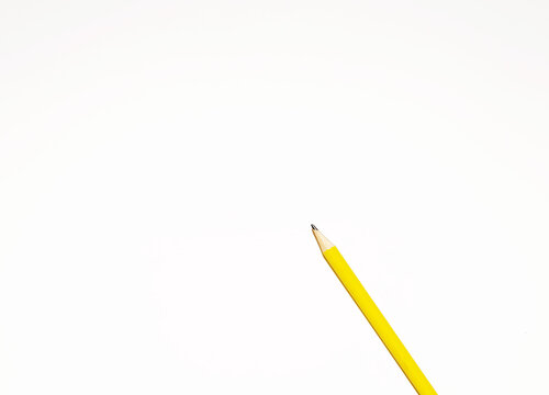 Presentation template with copy space by top view close up macro photo of wooden yellow pencil isolated on white paper that look minimalist and clean. Pencil on paper. Space for text.