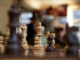wooden chessboard with the chess queen in focus and a blurred background
