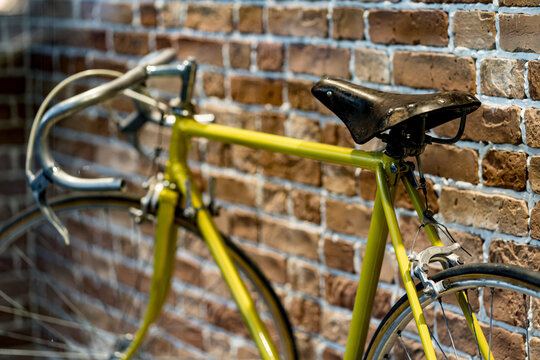 Retro yellow bicycle on roadside with vintage brick wall background