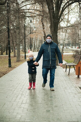 Father and son walk in the Park together. People are wearing protective masks.