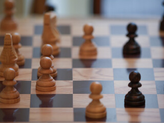 wooden chessboard with the chess queen in focus and a blurred background