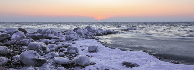 Snow and ice covered stones at the shore in winter, banner	