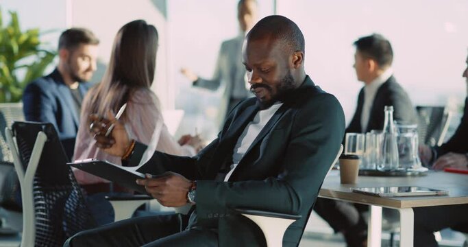 African american attractive businessman coworker in office company listening financial lec ture negotiation reading written notes.