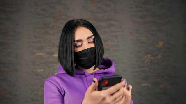 Frustated young brunette woman feeling upset using smartphone's face unlock feature wearing face mask
