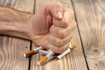 Do not smoke. Close-up of a male hand breaking a cigarette with a fist. Quit smoking