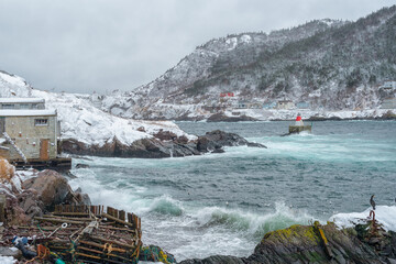 A winter's scene of St. John's harbor, Newfoundland. The sky is overcast. There's a lighthouse at the land's point along with small homes.  The bottom part of the picture has a marine marker   © Dolores  Harvey