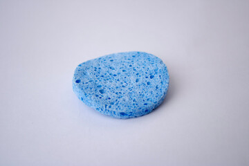 Blue round cosmetic sponge for face cleansing on white background.