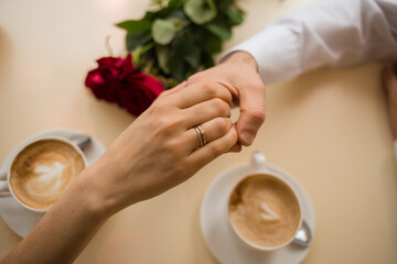hand to a woman with a wedding ring in her hand to a man on the table