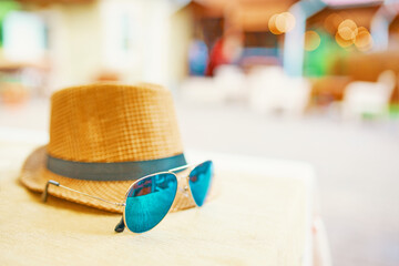 Hat and glasses on the table. Straw men's hat with a black ribbon. Mirrored sunglasses. Concept of...