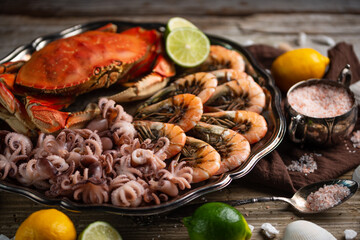 dish with set of seafood. Cooked tiger shrimps, crab and baby octopuses with citrus on rustic wooden background. Healthy delicious food. Restaurants menu meal.
