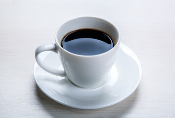 white cup with black coffee and saucer on the table