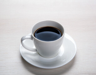 white cup with black coffee and saucer on the table