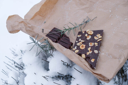 The handmade chocolate bar filled with nuts. Snow surface. Copy space.