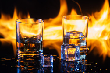 fire ice and glass of whiskey on black background