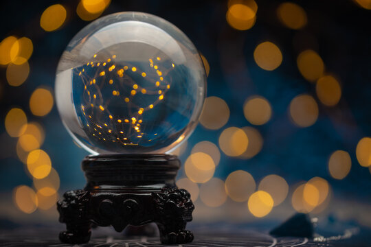 Crystal magic ball to predict the fate on yellow lights background. Guessing for the future. Astrology concept.