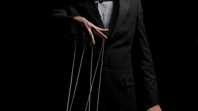 Puppeteer pulls the doll strings tied to his fingers. Puppet rope manipulation concept and control hand. Businessman controls the mind and actions of people. Close up. Slow motion.