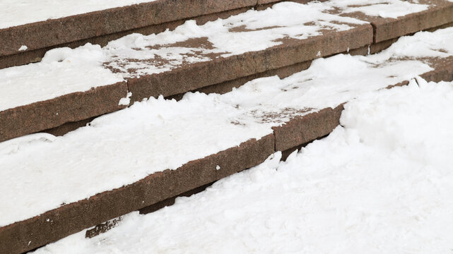 Snow covered slippery concrete stairs. First snow on granite stone steps.