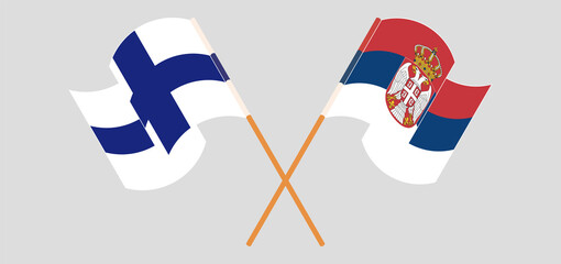 Crossed and waving flags of Finland and Serbia