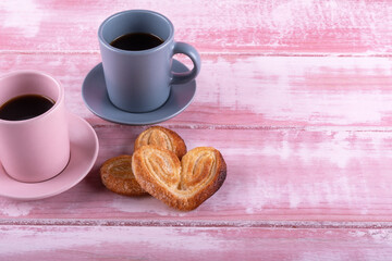 Two cups of coffe with two heart puff pastry on a pink wood for celebrate valentine's day. Free copy space. Concept valentine's day. Mother's day