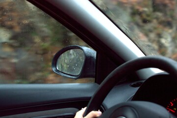 Hands of white woman car on rainy autumn or winter day driving on the road