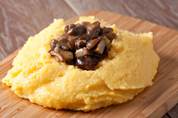 Polenta with mushroom. Traditional corn food in the plate.