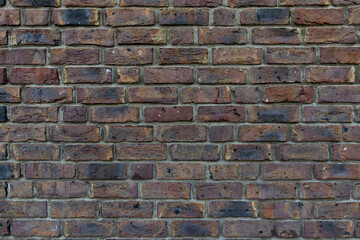 Close up of an old red orange brown worn and weathered brick wall, clinker bricks. Brick texture