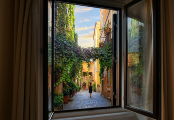View through an open window as a young woman walks through an ivy covered colorful alley in the Trastevere district of Rome, Italy