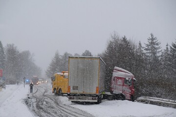 An accident on the road involving a truck in very difficult winter conditions. Roadside assistance during an accident. © Iwona