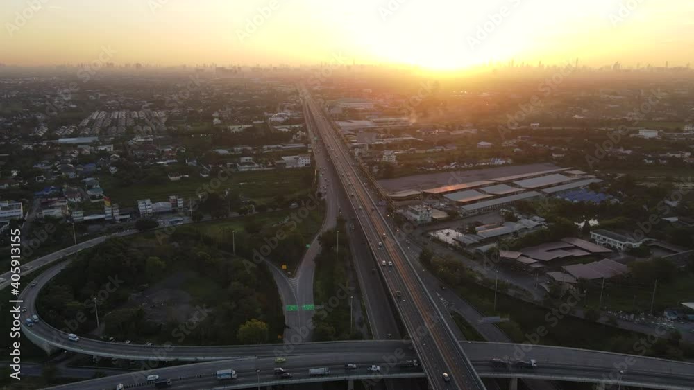Wall mural 4K. Aerial view of road interchange or highway intersection during sunrise with busy urban traffic speeding on the road. Junction network of transportation taken by drone. - Wall murals