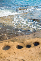 Holes carved in stone by the beach