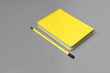 Yellow notepad with yellow pencil on gray background