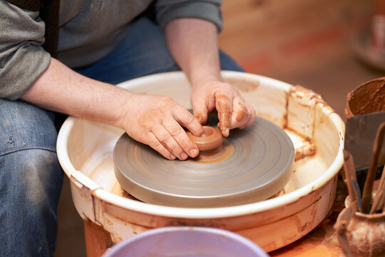 Pottery workshop. A cut-off image of a potter working with clay on a potter's wheel.