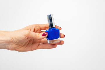Female hand holding nail polish against white background