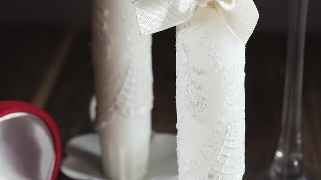 champagne and two white wedding candles with wedding rings, slide shot, close-up.