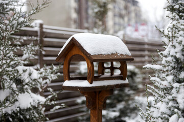 Snow-covered bird feeder in the courtyard of a village house on  cloudy winter day.