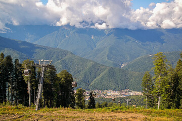 View of the mountains, overgrown with dense deciduous and coniferous forests, with modern transport, including lifts for mountain skiers and economic communications for the active recreation of people