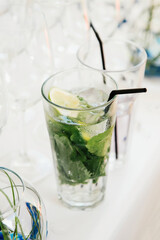 a delicious fresh drink of water with lime and mint stands on a table with a white tablecloth