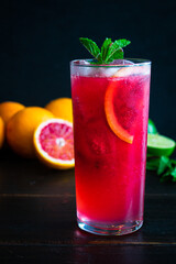 Blood Orange and Raspberry Mojito: A rum cocktail with blood oranges, raspberries, lime, and mint leaves served in a tall glass over ice