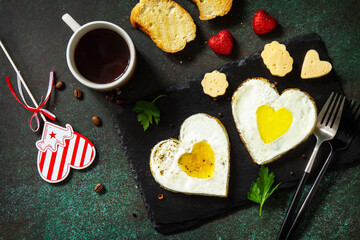 Breakfast on Valentines Day or brunch. Heart shape fried egg on slate plate. Top view flat lay.