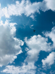 A plane that flies in the blue sky among the white lush clouds. Bright sunny day