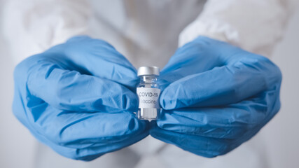 Doctor hand holds a Coronavirus vaccine bottle. Stopping the Covid-19 pandemic concept.