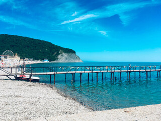 Pier which goes into the blue sea on a bright sunny day