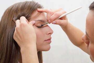 Obraz premium The process of creating makeup. Makeup artist working with a brush on the face of the model.