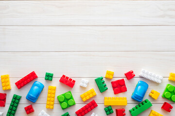 Colorful plastic toy blocks. Colorful plastic toy blocks on white wooden background with copy space. Top view. Baby background