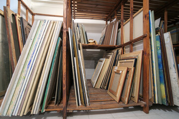 Wooden shelves at art gallery storage full of pictures and art equipment - obrazy, fototapety, plakaty