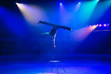A man of athletic build performs complex gymnastic exercises in the circus arena.