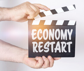 On a white background, a man holds a clapperboard in his hands on which it is written - ECONOMY...