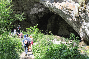 A cave in the mountain. A group of travelers on vacation go to the grotto. Concept sport, tourism.