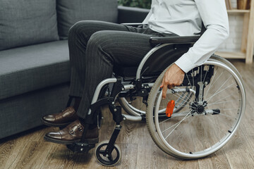 Disabled man tries to sit down on a sofa from wheelchair