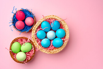 Painted Easter eggs in decorative nest on pink background